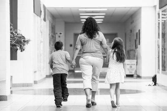 teacher walking down the hall hand-in-hand with 2 young students