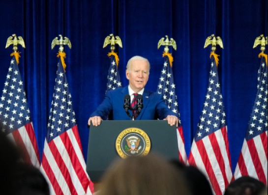 President Biden at a podium in front of a row of American flags